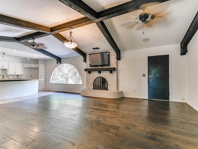 212 W Ridgewood Dr, Midwest City, OK 73130 - unfurnished living room with ceiling fan, beamed ceiling, hardwood / wood-style flooring, a fireplace, and baseboards