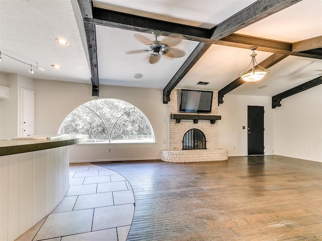 212 W Ridgewood Dr, Midwest City, OK 73130 - unfurnished living room with beamed ceiling, a fireplace, ceiling fan, and wood finished floors