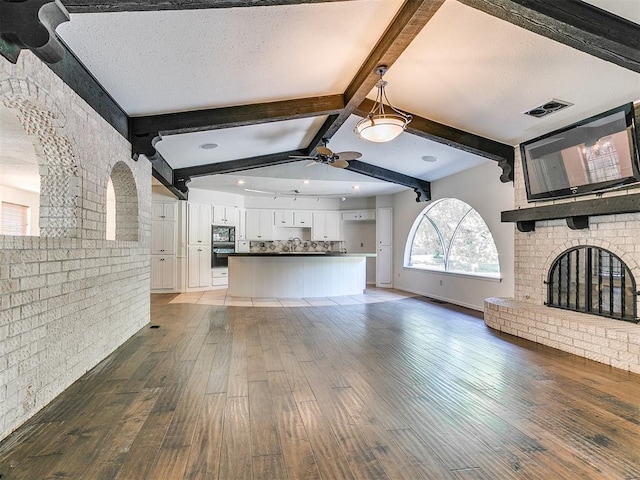 212 W Ridgewood Dr, Midwest City, OK 73130 - unfurnished living room with wood finished floors, ceiling fan, and a brick fireplace