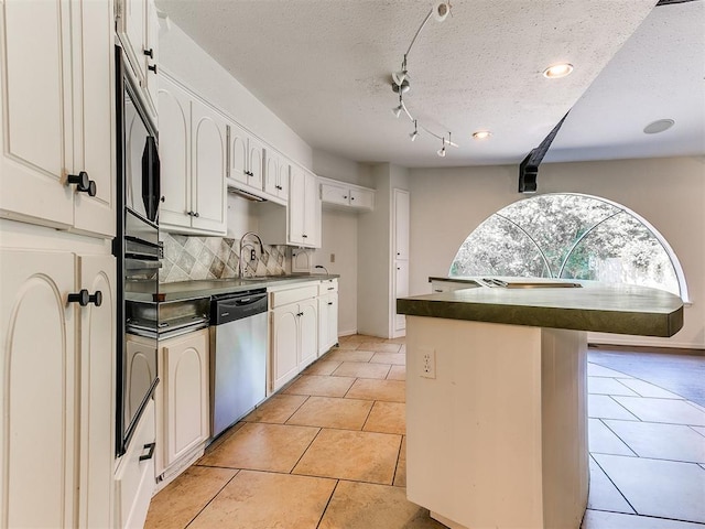212 W Ridgewood Dr, Midwest City, OK 73130 - kitchen featuring dishwasher, dark countertops, backsplash, light tile patterned floors, and a textured ceiling