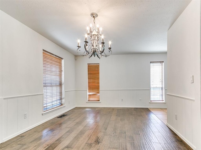 212 W Ridgewood Dr, Midwest City, OK 73130 - unfurnished room featuring wood finished floors, a chandelier, wainscoting, and a textured ceiling