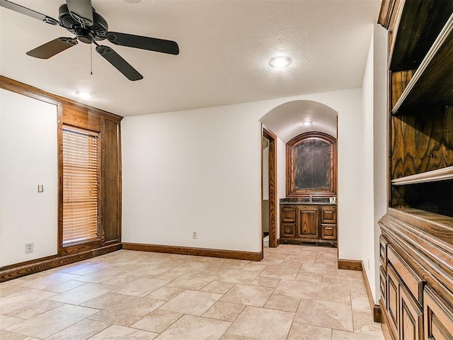 212 W Ridgewood Dr, Midwest City, OK 73130 - unfurnished room with a ceiling fan, baseboards, arched walkways, and light stone finish flooring