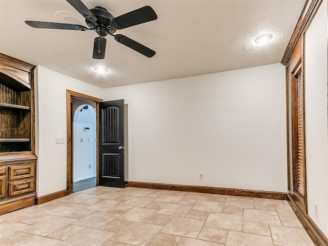 212 W Ridgewood Dr, Midwest City, OK 73130 - unfurnished bedroom featuring baseboards, a textured ceiling, ceiling fan, and light stone finish floors