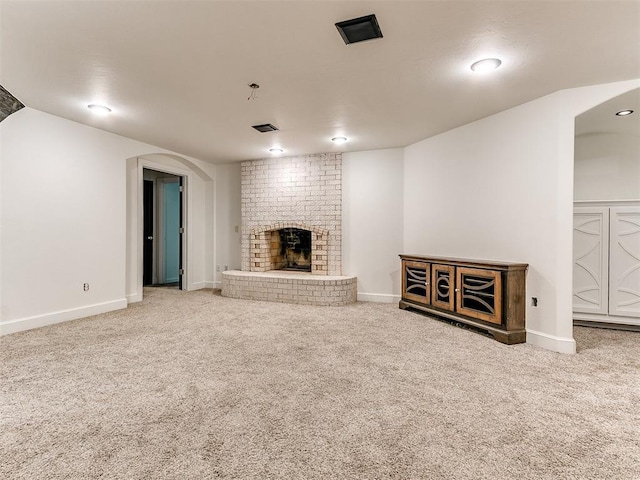 212 W Ridgewood Dr, Midwest City, OK 73130 - unfurnished living room featuring carpet flooring, a fireplace, arched walkways, and baseboards