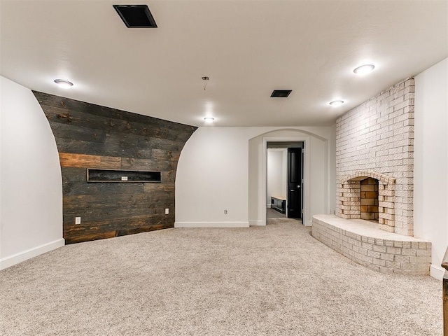 212 W Ridgewood Dr, Midwest City, OK 73130 - unfurnished living room featuring carpet flooring, a brick fireplace, arched walkways, baseboards, and wooden walls