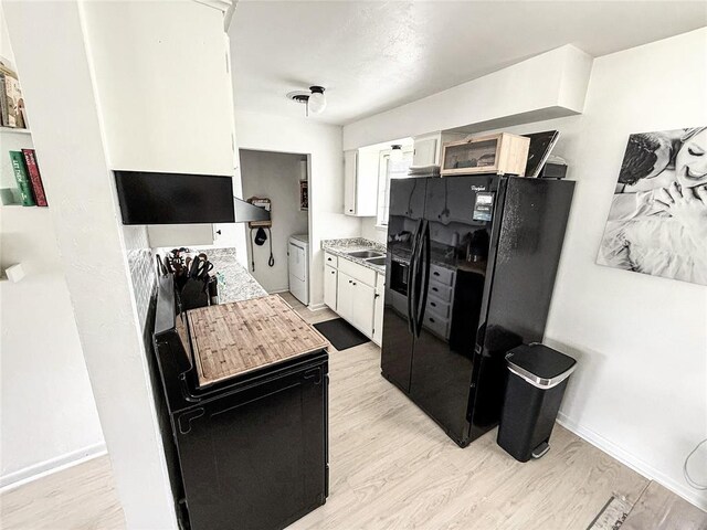 703 S 2nd Ave, Purcell, OK 73080 - kitchen featuring independent washer and dryer, black refrigerator with ice dispenser, light wood finished floors, and white cabinetry