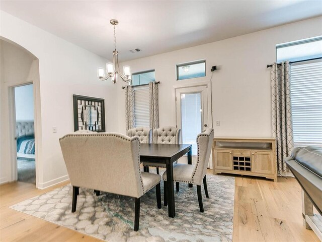 16125 Buffalo Dr, Moore, OK 73170 - dining area featuring arched walkways, a chandelier, light wood-style flooring, and healthy amount of natural light