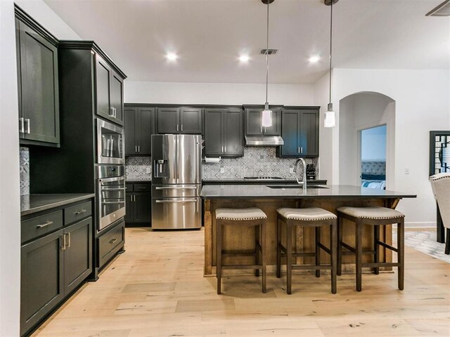 16125 Buffalo Dr, Moore, OK 73170 - kitchen with stainless steel appliances, a sink, dark countertops, arched walkways, and decorative backsplash