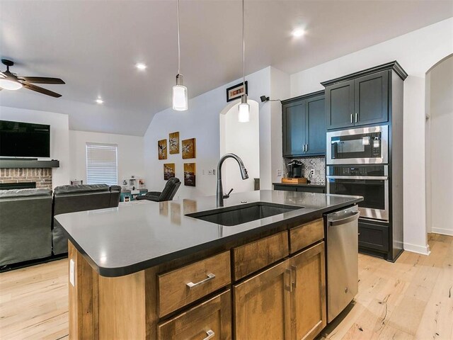 16125 Buffalo Dr, Moore, OK 73170 - kitchen featuring a sink, stainless steel appliances, arched walkways, light wood-style floors, and lofted ceiling