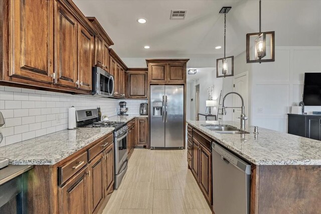 7224 NW 146th St, Oklahoma City, OK 73142 - kitchen with stainless steel appliances, a sink, an island with sink, light stone counters, and decorative backsplash
