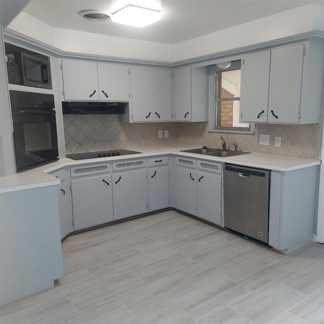 7123 NW 44th St, Bethany, OK 73008 - kitchen with black appliances, a sink, under cabinet range hood, decorative backsplash, and light countertops