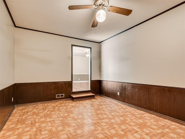 4809 N Pate Ave, Oklahoma City, OK 73112 - unfurnished room with a wainscoted wall, wooden walls, a ceiling fan, crown molding, and parquet flooring