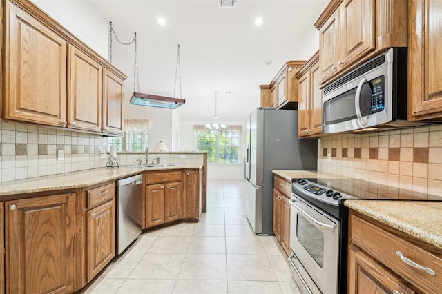 2632 SE 97th St, Moore, OK 73160 - kitchen featuring stainless steel appliances, a sink, brown cabinets, light tile patterned floors, and recessed lighting