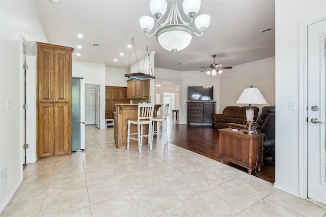 2632 SE 97th St, Moore, OK 73160 - kitchen with brown cabinets, a ceiling fan, freestanding refrigerator, open floor plan, and a breakfast bar area