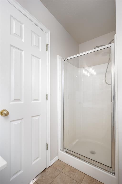 1704 Sumac Dr, Norman, OK 73071 - bathroom featuring a shower stall, tile patterned flooring, and baseboards
