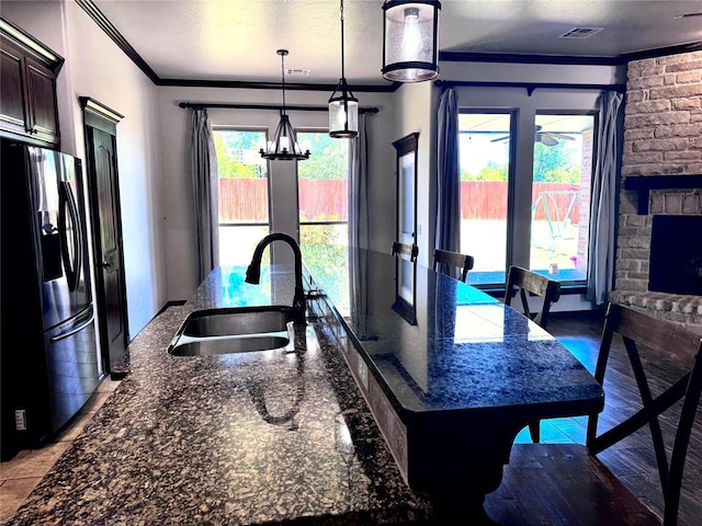3001 Flint Ct, Oklahoma City, OK 73165 - kitchen featuring stainless steel fridge with ice dispenser, a sink, ornamental molding, an island with sink, and dark stone counters