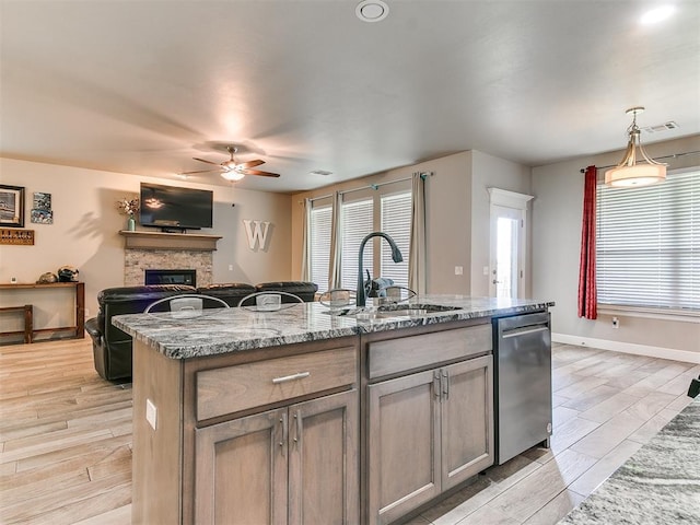 1405 Atalon Dr, Moore, OK 73160 - kitchen featuring dishwasher, a sink, a ceiling fan, a stone fireplace, and light stone counters