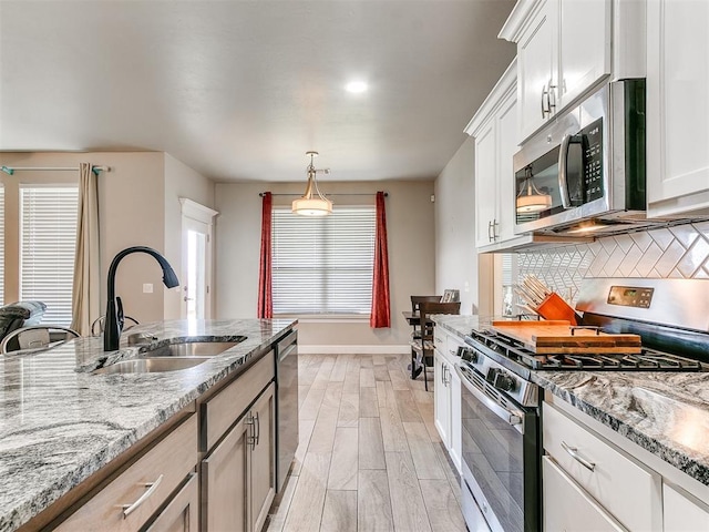 1405 Atalon Dr, Moore, OK 73160 - kitchen featuring appliances with stainless steel finishes, a sink, tasteful backsplash, light stone counters, and baseboards