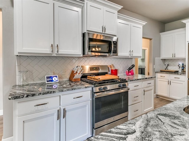 1405 Atalon Dr, Moore, OK 73160 - kitchen featuring appliances with stainless steel finishes, decorative backsplash, dark stone countertops, and white cabinetry