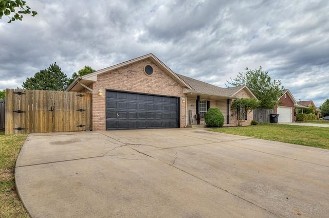 2121 NE 13th St, Moore, OK 73160 - single story home with brick siding, an attached garage, driveway, and a gate
