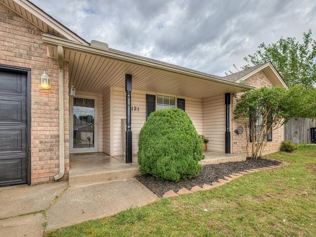 2121 NE 13th St, Moore, OK 73160 - doorway to property featuring brick siding, a porch, and a lawn