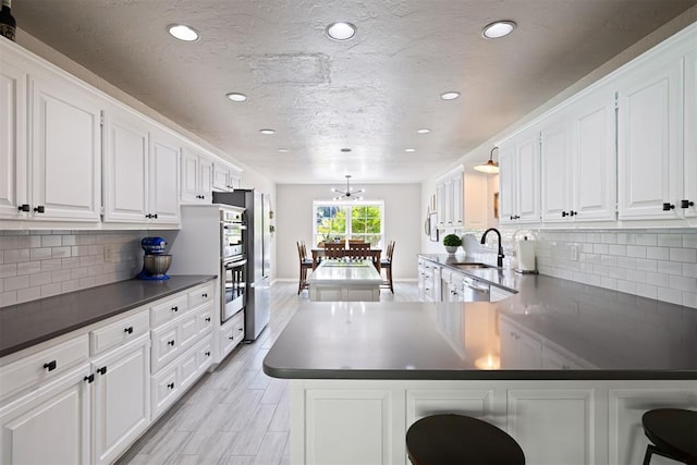 1704 Faircloud Dr, Edmond, OK 73034 - kitchen with dark countertops, recessed lighting, a sink, and white cabinetry