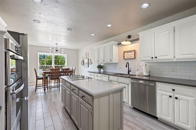1704 Faircloud Dr, Edmond, OK 73034 - kitchen with stainless steel appliances, a sink, a chandelier, a kitchen island, and backsplash