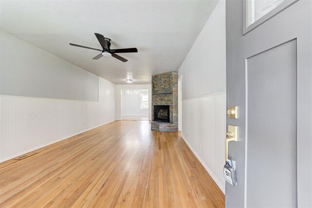 1206 Monroe Dr, Shawnee, OK 74804 - unfurnished living room with light wood finished floors, ceiling fan, a fireplace, and wainscoting