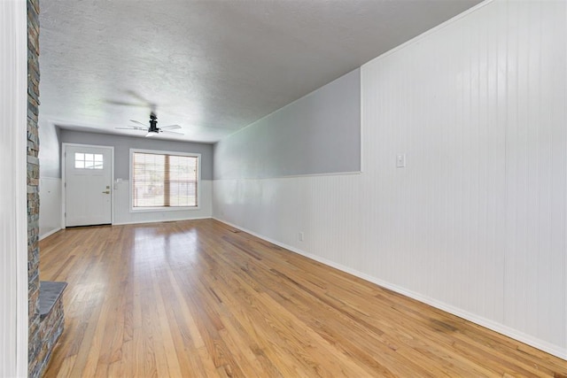 1206 Monroe Dr, Shawnee, OK 74804 - unfurnished living room with a ceiling fan, light wood finished floors, baseboards, and a textured ceiling