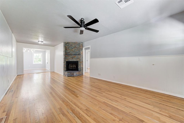 1206 Monroe Dr, Shawnee, OK 74804 - unfurnished living room with light wood finished floors, a ceiling fan, a stone fireplace, a chandelier, and baseboards