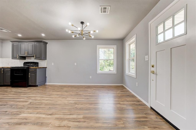 1206 Monroe Dr, Shawnee, OK 74804 - kitchen featuring electric range, gray cabinets, a chandelier, backsplash, and light wood-style floors