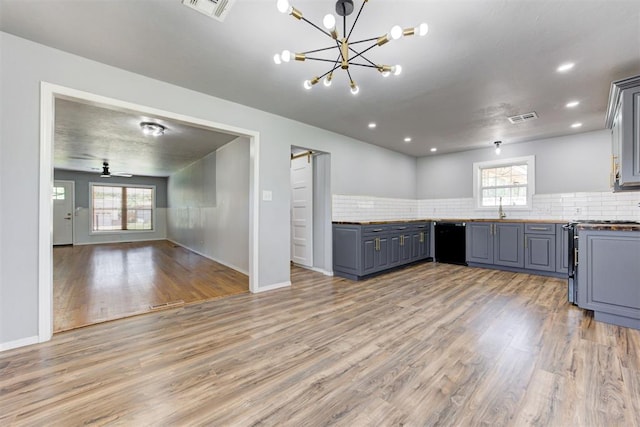 1206 Monroe Dr, Shawnee, OK 74804 - kitchen featuring dishwasher, a sink, open floor plan, light wood-style floors, and decorative backsplash