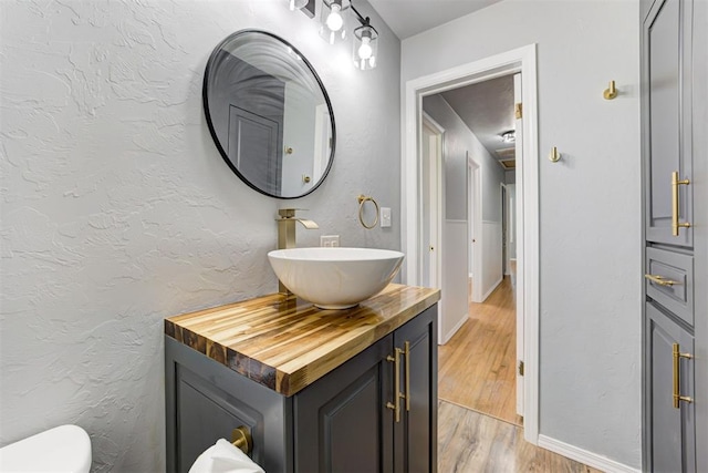 1206 Monroe Dr, Shawnee, OK 74804 - bathroom with vanity, wood finished floors, toilet, and baseboards