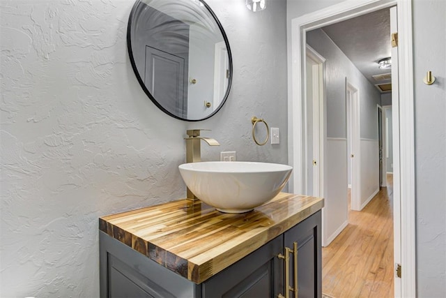 1206 Monroe Dr, Shawnee, OK 74804 - bathroom with wood finished floors, vanity, and a textured wall