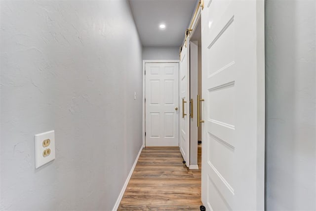 1206 Monroe Dr, Shawnee, OK 74804 - hallway featuring a barn door, wood finished floors, baseboards, and recessed lighting