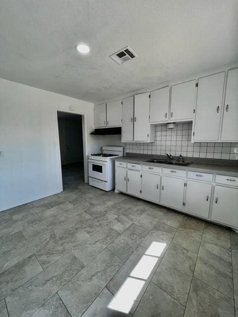 1228 Santa Fe Dr, Clinton, OK 73601 - kitchen with white range with gas stovetop, a sink, under cabinet range hood, white cabinetry, and recessed lighting
