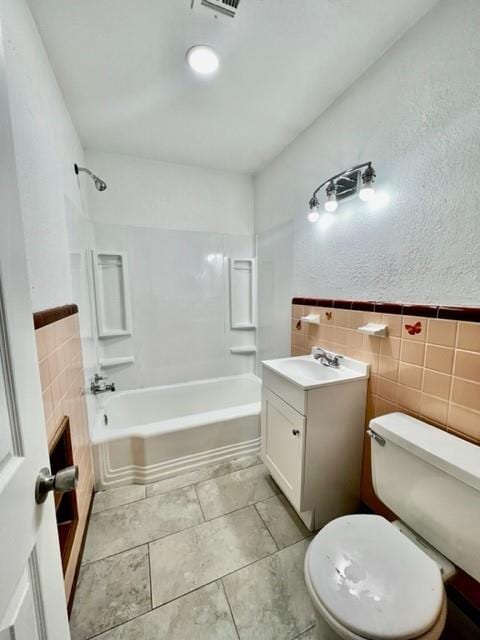 1228 Santa Fe Dr, Clinton, OK 73601 - full bath featuring tile walls, toilet, shower / washtub combination, vanity, and wainscoting
