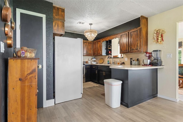 32629 S Airline Rd, Pauls Valley, OK 73075 - kitchen featuring freestanding refrigerator, light wood-style flooring, light countertops, a textured ceiling, and a peninsula