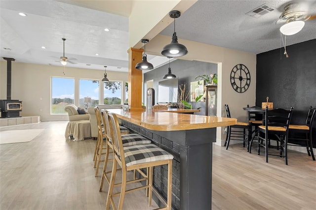 32629 S Airline Rd, Pauls Valley, OK 73075 - kitchen with ceiling fan, a wood stove, light wood-style floors, a breakfast bar, and recessed lighting