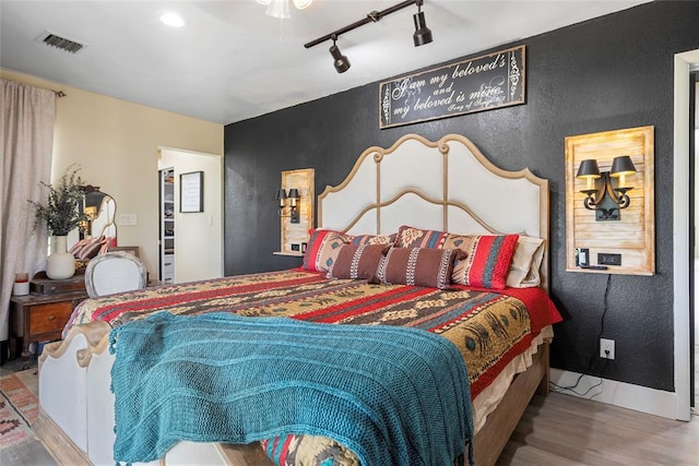 32629 S Airline Rd, Pauls Valley, OK 73075 - bedroom featuring wood finished floors, rail lighting, a textured wall, and a ceiling fan