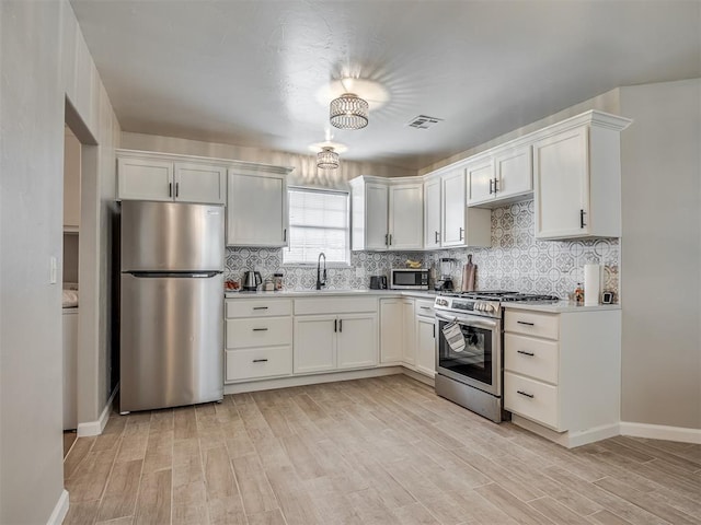 4100 S Noma Rd, Oklahoma City, OK 73150 - kitchen featuring appliances with stainless steel finishes, a sink, light wood finished floors, tasteful backsplash, and light countertops