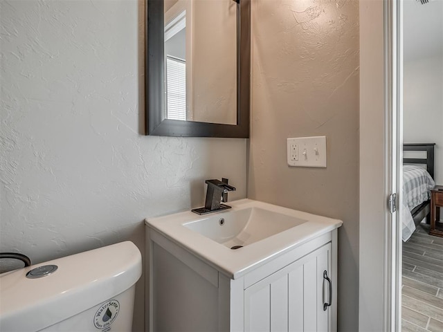 4100 S Noma Rd, Oklahoma City, OK 73150 - bathroom featuring vanity, a textured wall, wood finished floors, ensuite bath, and toilet
