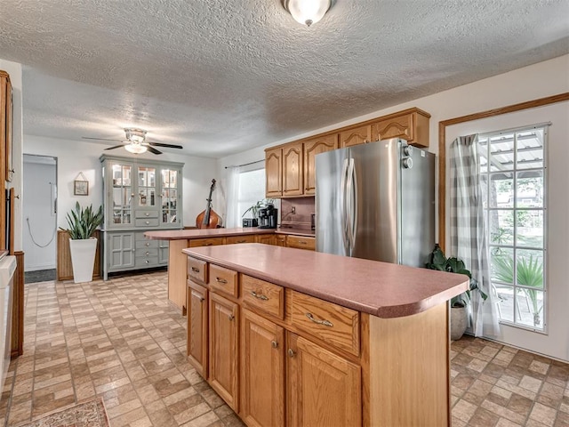 303 W Meek St, Wayne, OK 73095 - kitchen featuring freestanding refrigerator, a peninsula, ceiling fan, a kitchen island, and a textured ceiling