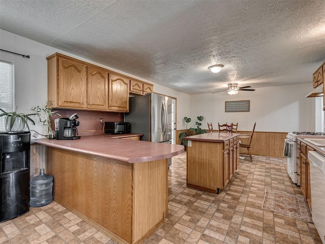 303 W Meek St, Wayne, OK 73095 - kitchen with white appliances, a peninsula, wainscoting, a center island, and brick patterned floors