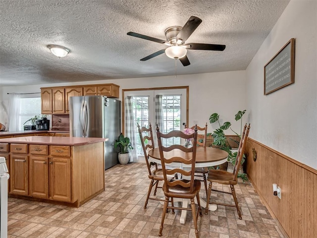 303 W Meek St, Wayne, OK 73095 - dining room featuring wooden walls, a ceiling fan, healthy amount of natural light, a wainscoted wall, and a textured ceiling