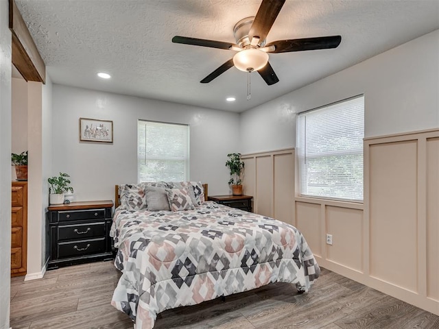 303 W Meek St, Wayne, OK 73095 - bedroom featuring light wood-style flooring, a decorative wall, a textured ceiling, wainscoting, and recessed lighting