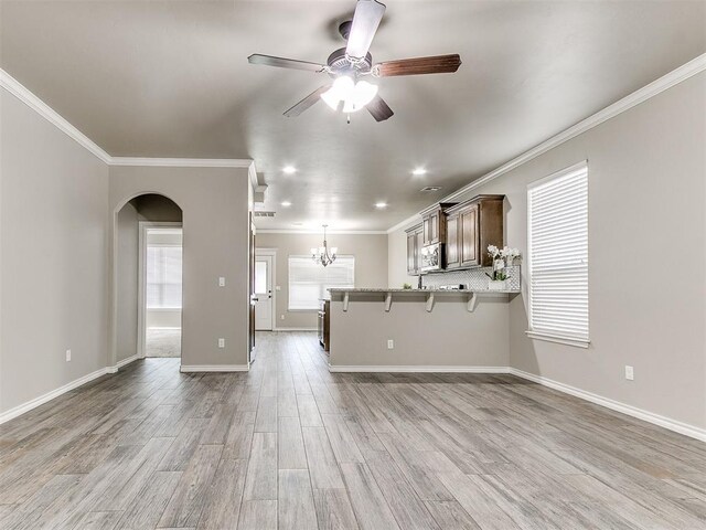 8344 NW 137th St, Oklahoma City, OK 73142 - unfurnished living room featuring crown molding, ceiling fan, arched walkways, light wood finished floors, and a chandelier