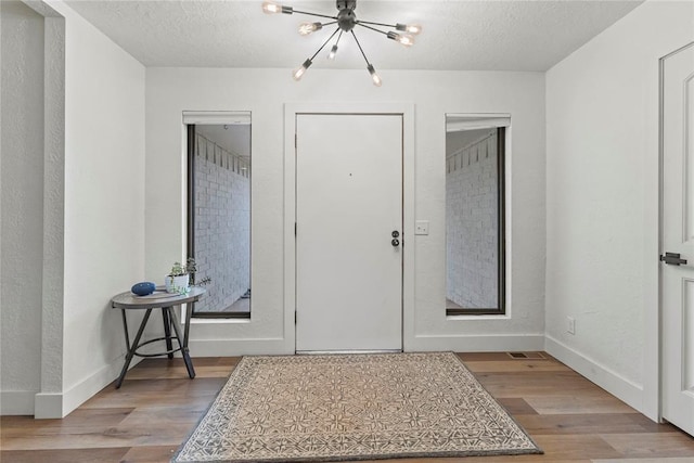 1206 N Kaiser Rd, Weatherford, OK 73096 - foyer featuring a chandelier, wood finished floors, a textured ceiling, and baseboards