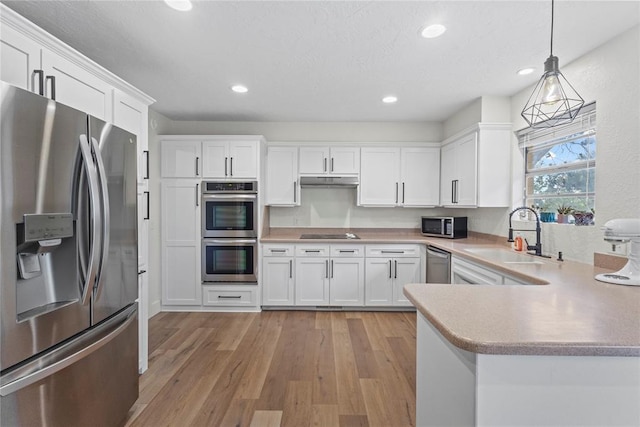 1206 N Kaiser Rd, Weatherford, OK 73096 - kitchen with appliances with stainless steel finishes, a sink, white cabinetry, light wood-type flooring, and decorative light fixtures