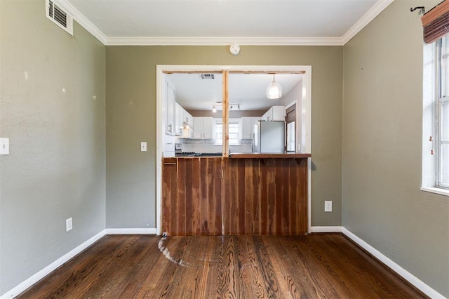 3901 NW 56th Pl, Oklahoma City, OK 73112 - unfurnished dining area with dark wood-style flooring, baseboards, and crown molding